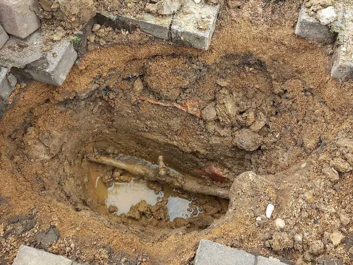 The excavated driveway at Grantham, showing waterlogged soil around the buried lead supply pipe